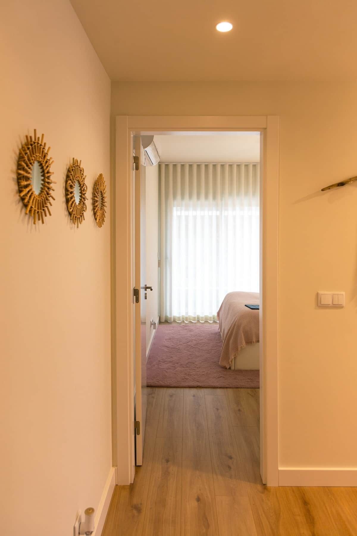 Ein Flur, der in ein Schlafzimmer mit einem Bett und einer Tür sowie drei Wanddekorationen führt.