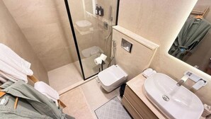 A modern bathroom with a glass-enclosed shower, a white sink, and a toilet.
