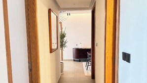 A hallway with wooden doors, a patterned rug, and a ceiling light fixture.