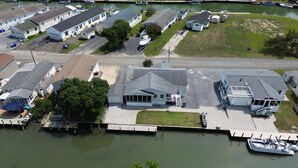 A marina with several docked boats, a small house with a garage, and a large building with a sloped roof. - Incredible 3-bedroom house WITH BOAT DOCK on Rehoboth Bay (Millsboro)