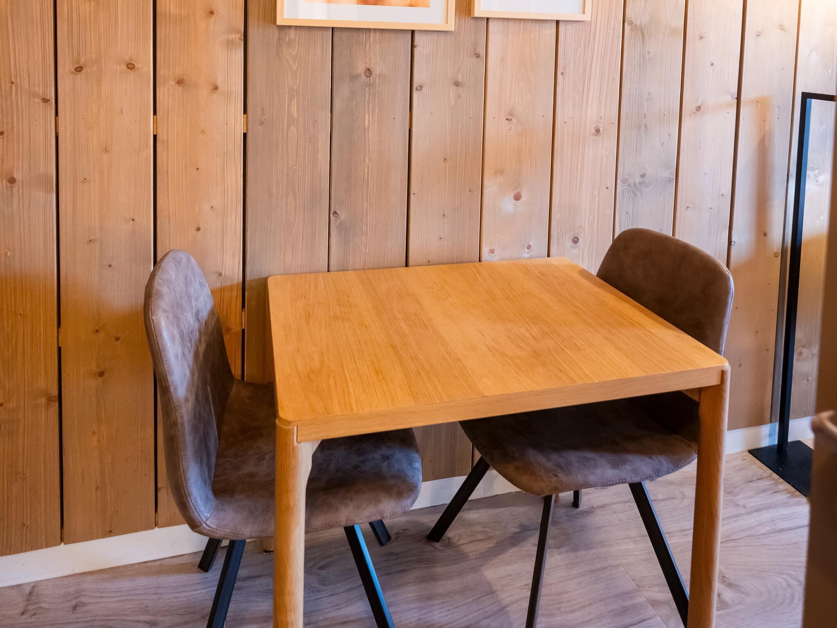 Ein Holztisch mit zwei Stühlen, eine Holzwand und ein Holzboden.