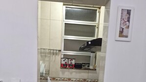 Een kleine keuken met een gasfornuis, een blender en een klein raam boven de gootsteen.