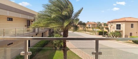 Un barrio residencial con cielo despejado, una palmera y casas con techos de tejas rojas.