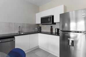 A modern kitchen with white cabinets, a stainless steel refrigerator, a microwave, and a coffee maker. - Stylish Gold Coast Condo Sunrise by Bocobay (Noord)