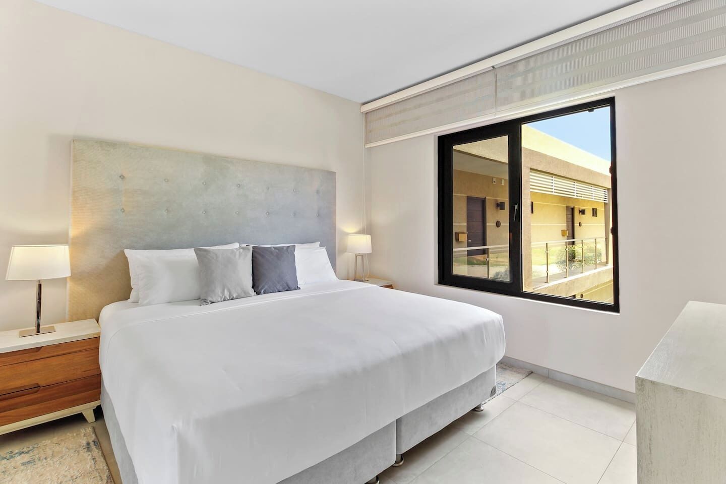 Quarto de hotel com uma cama grande, duas mesas de cabeceira, uma janela com vista e um design moderno na parede.