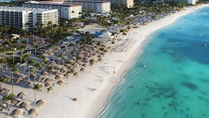A beach resort with multiple hotel buildings, a sandy beach, and thatched umbrellas. - Stylish Gold Coast Condo Sunrise by Bocobay (Noord)