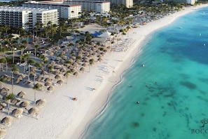 A beach resort with multiple hotel buildings, a sandy beach, and thatched umbrellas. - Stylish Gold Coast Condo Sunrise by Bocobay (Noord)