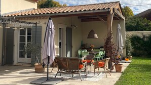 Una zona de terrassa coberta amb mobles d'exterior, taula de dinar i plantes en testos.