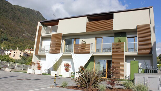 Un bâtiment moderne à deux étages, doté d’un balcon, de grandes fenêtres et surplombant un paysage montagneux.