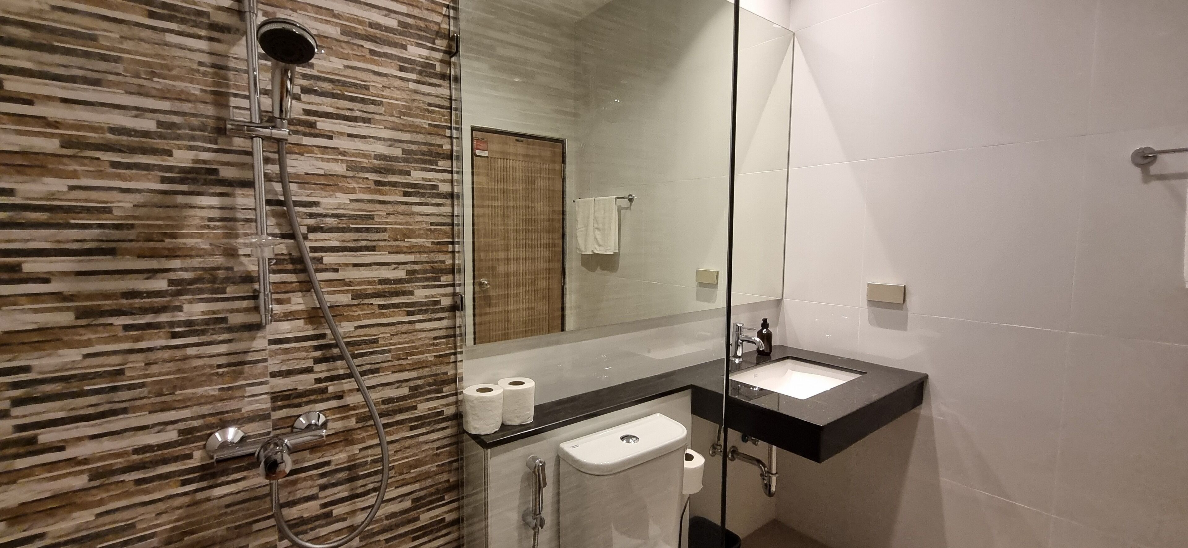 A modern bathroom with a shower, a sink, and a toilet.