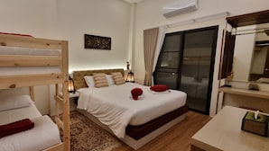 Ein Hotelzimmer mit einem Etagenbett, einem Einzelbett, einem Nachttisch mit Lampe, einem kleinen Teppich und einem Fenster mit Vorhängen.