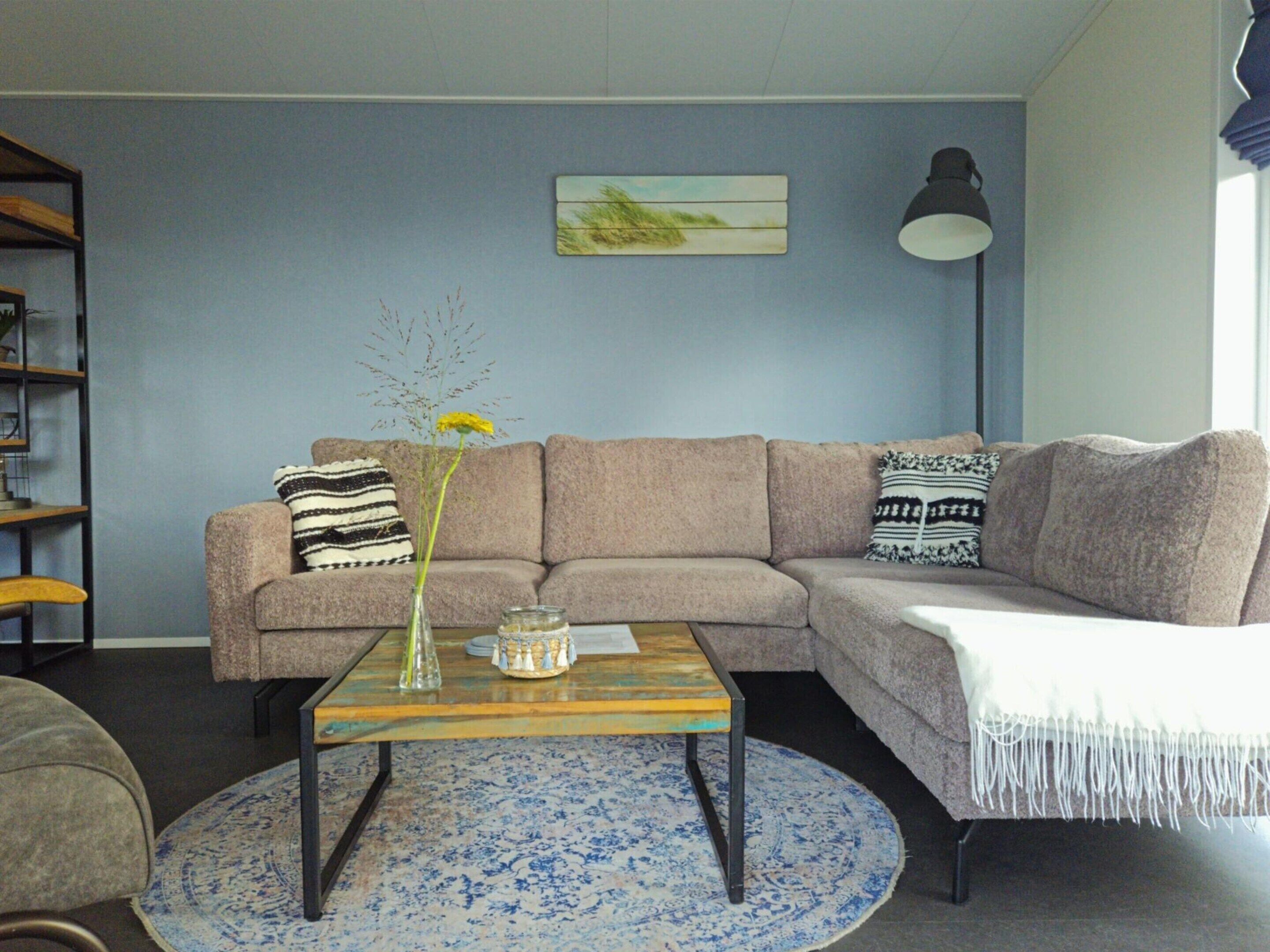 A living room with a sofa, a coffee table, a lamp, and a vase with flowers.
