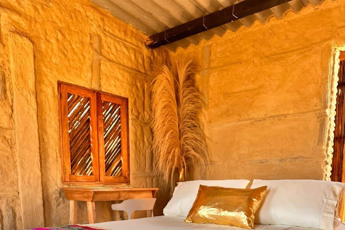 Une pièce avec un lit, une table en bois et une fenêtre ornée de volets à motifs.