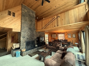 Ein gemütliches Blockhaus-Interieur mit Kamin aus Stein, Holzboden und einer grossen Couch.
