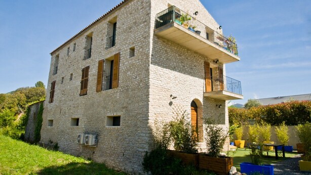 Un bâtiment en pierre doté d’un balcon et d’un petit jardin.