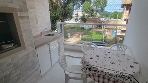Ein Balkon mit einem kleinen Tisch und Stühlen, einem Waschbecken und Blick auf ein Wohngebiet.