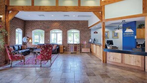 A spacious lobby with a brick wall, wooden beams, and a reception desk. - Spacious 2-Bedroom Williamsburg Escape, Just Moments from Busch Gardens (Williamsburg)