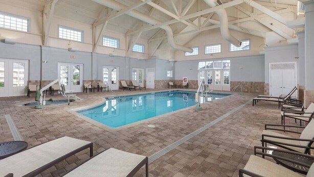 An indoor swimming pool with tiled flooring, lounge chairs, and a high ceiling with exposed beams. - Spacious 2-Bedroom Williamsburg Escape, Just Moments from Busch Gardens (Williamsburg)