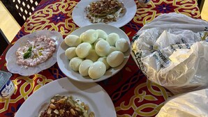 Un tavolo da pranzo con diversi piatti, bottiglie d'acqua e sacchetti di plastica.