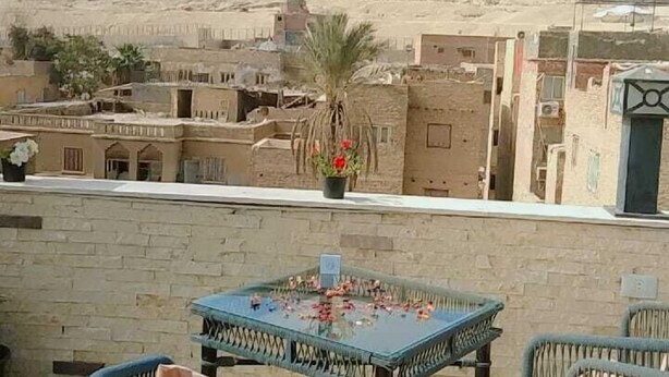 Una terrazza con sedie in vimini e un tavolo, con vista sulle piramidi.