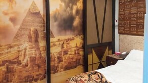 Una camera da letto con un murale delle piramidi egizie, un letto con biancheria a motivi decorativi e una lampada a soffitto decorativa.