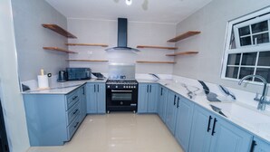 Una cocina con gabinetes azules, estufa, microondas y ventana.