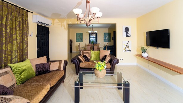Una sala de estar con sofá, mesa de centro, televisor y candelabro.