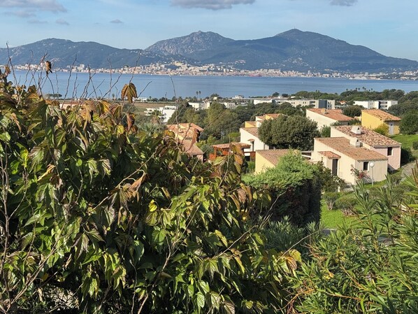 Eine Küstenstadt mit Gebäuden im mediterranen Stil, Blick auf das Meer und Berge im Hintergrund.