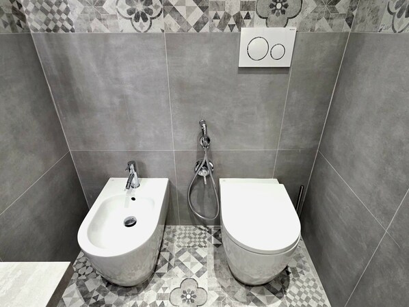 A bathroom with a bidet, toilet, and a shower. - VICTORIA SUITES (Rome)