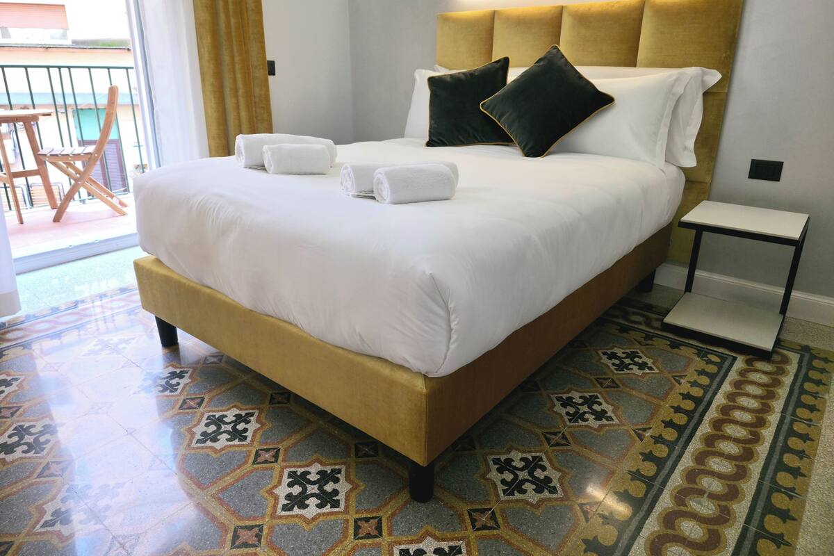 A hotel room with a large bed, a bedside table, and a view of the outside balcony.
