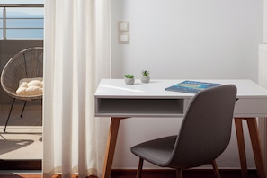 Ein modernes Zimmer mit einem weißen Schreibtisch, einem grauen Stuhl, zwei kleinen Topfpflanzen und einem Buch mit dem Titel 'The Art of War'.