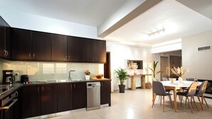 A modern kitchen with dark cabinets, a dishwasher, and a dining area with a table and chairs.