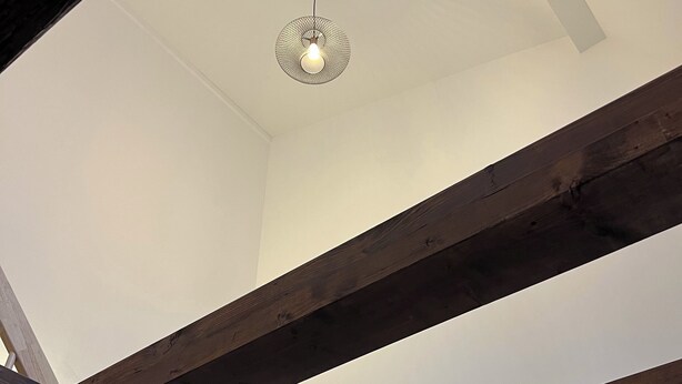 A room with exposed wooden beams and a hanging light fixture. - Modern 1-room apartment in a historic setting next to the New Palace (Bayreuth)