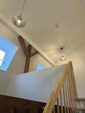 Eine Treppe mit Holzwertlauf und Decke mit Oberlichtern und Pendelleuchten.