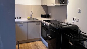 A modern kitchen with white cabinets, a black countertop, and a built-in oven. - Modern 1-room apartment in a historic setting next to the New Palace (Bayreuth)