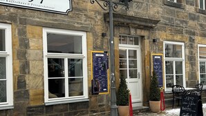 A stone building with a sign reading "1897" and a blackboard with menu items. - Modern 1-room apartment in a historic setting next to the New Palace (Bayreuth)