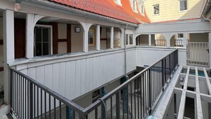 A multi-story building with a red-tiled roof, white railings, and a covered outdoor area with a gravel floor. - Modern 1-room apartment in a historic setting next to the New Palace (Bayreuth)