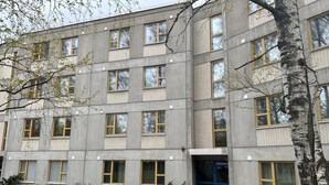 A multi-story building with a symmetrical facade, featuring evenly spaced windows and a central entrance with a blue door. - Spacious 2 Bedroom 75 sqm Kannelmäki (Helsinki)