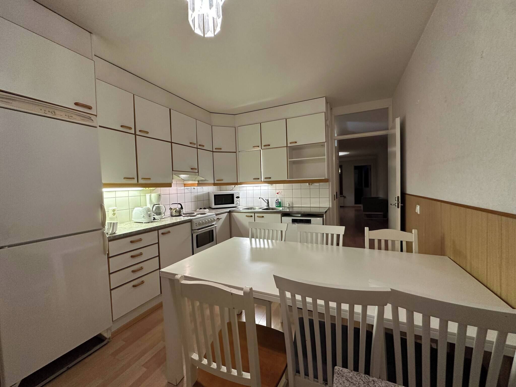 A compact kitchen with white cabinets, a dining table, and chairs.