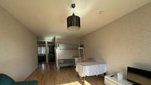 A modern living room with a sofa, a TV, a table, and a bunk bed. - Spacious 2 Bedroom 75 sqm Kannelmäki (Helsinki)