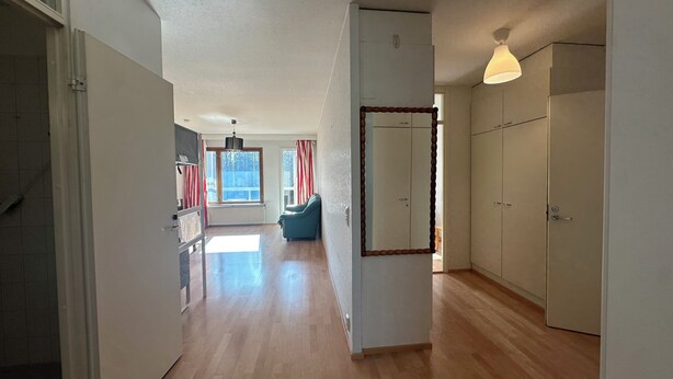 A spacious hallway with wooden flooring, a blue armchair, a large mirror, and a wardrobe. - Spacious 2 Bedroom 75 sqm Kannelmäki (Helsinki)