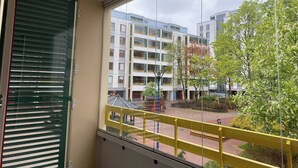 A balcony with a view of a courtyard, featuring modern buildings and a tree. - Lovely 2-br 77m2 Apart Pasila-train Station (Helsinki)