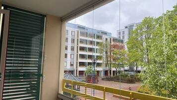 A balcony with a view of a courtyard, featuring modern buildings and a tree.