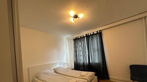 A bedroom with a bed, a chair, and a window with curtains. - Lovely 2-br 77m2 Apart Pasila-train Station (Helsinki)