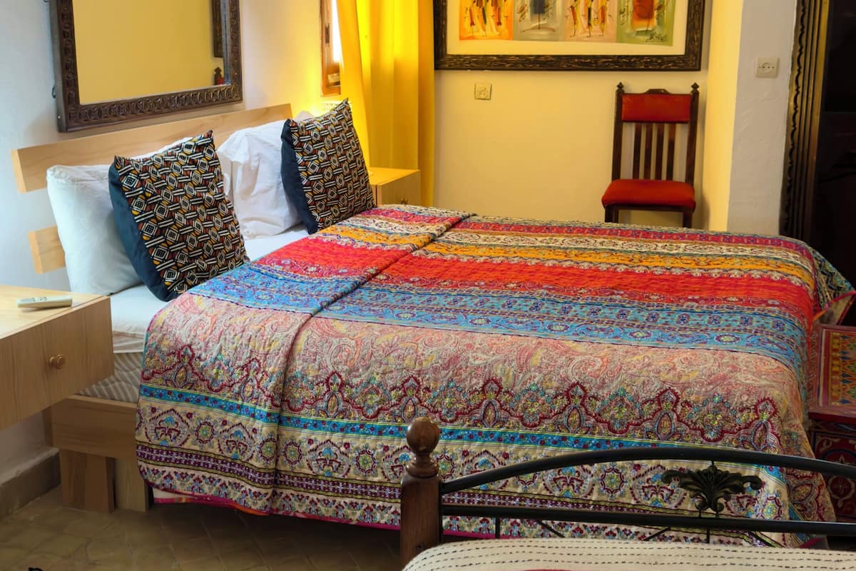 Quarto com duas camas, um espelho grande, uma obra de arte emoldurada e uma cadeira.