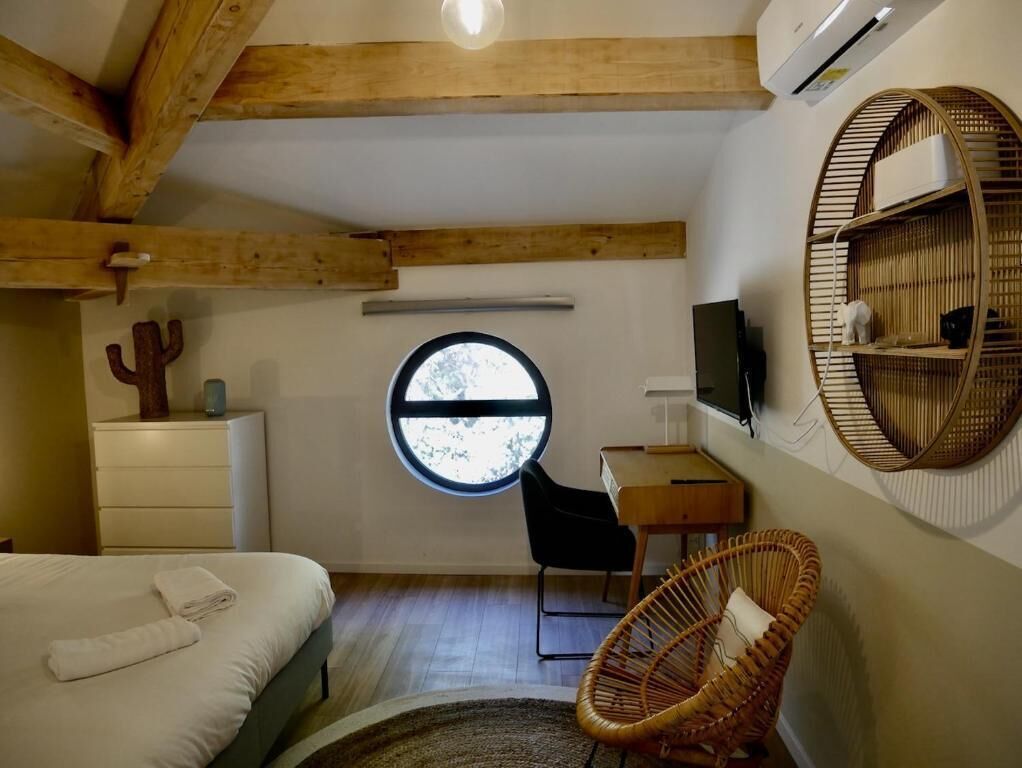 Una camera da letto con un letto, una finestra rotonda, una scrivania, una sedia e un televisore a parete.