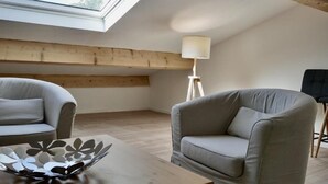 Un dormitori tipus loft amb un fanal, un sofà, una taula amb un bol decoratiu i una làmpada de peu.