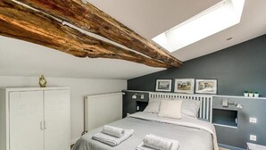 A bedroom with a skylight, a bed with towels, a wardrobe, and a radiator. - La demeure de Gab  (Trévoux)