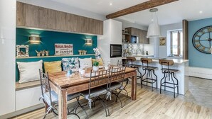 A modern kitchen with wooden cabinets, a central island, and bar stools. - La demeure de Gab  (Trévoux)