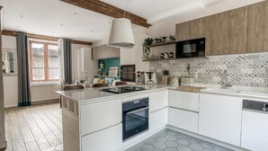 A modern kitchen with a central island, built-in oven, and a microwave. - La demeure de Gab  (Trévoux)
